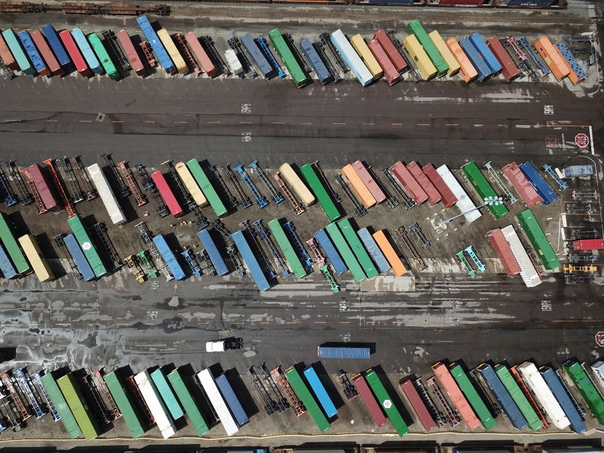 Aerial shot of multicolored shipping containers in an organized layout at a port.